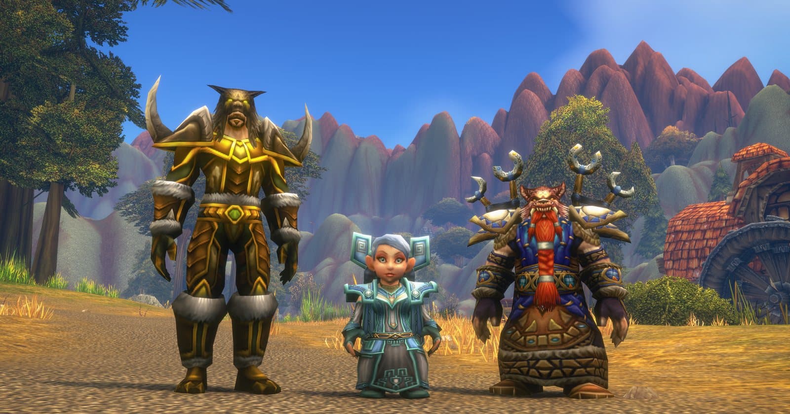 A tauren in gold armour, a gnome in blue robes and a dwarf with totems on the shoulders, standing on a dirt road below red cliffs