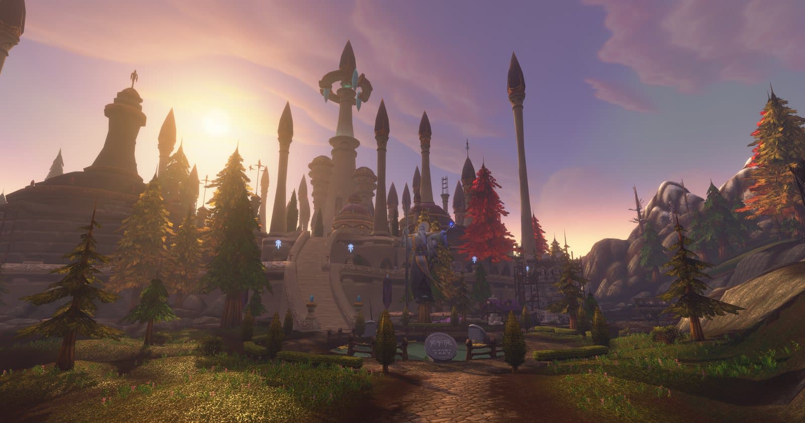 The spires of Dalaran at sunset behind pine and red-leaved trees, with a stone path leading up to a wide stair and a statue of a mage