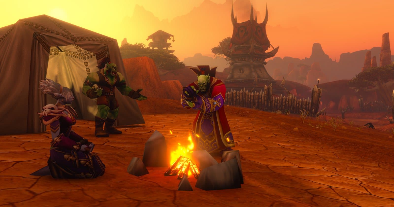 Three players at a campfire beside a tent in the Barrens at sunset, with the Crossroads tower behind them